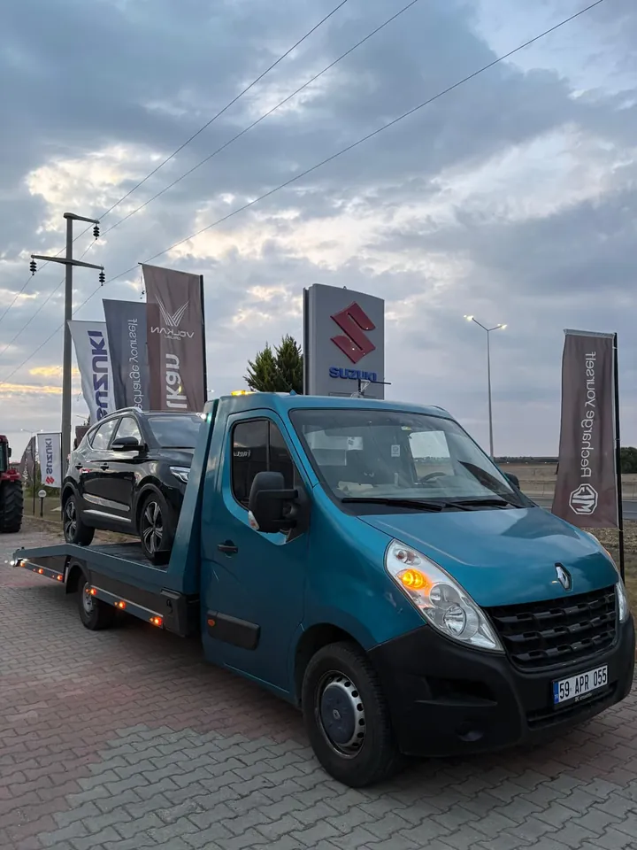 Bayi önünde siyah SUV taşıyan platformlu çekici, gün batımında