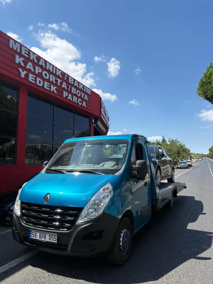 Oto servis önünde gri otomobili taşıyan platformlu çekici