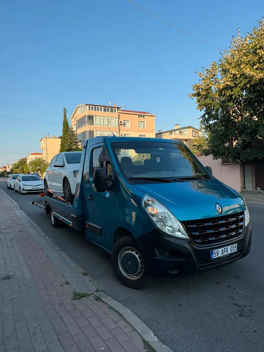 Mert Oto Kurtarma platformlu çekicisi, beyaz otomobili yüklenmiş halde mahalle sokağında
